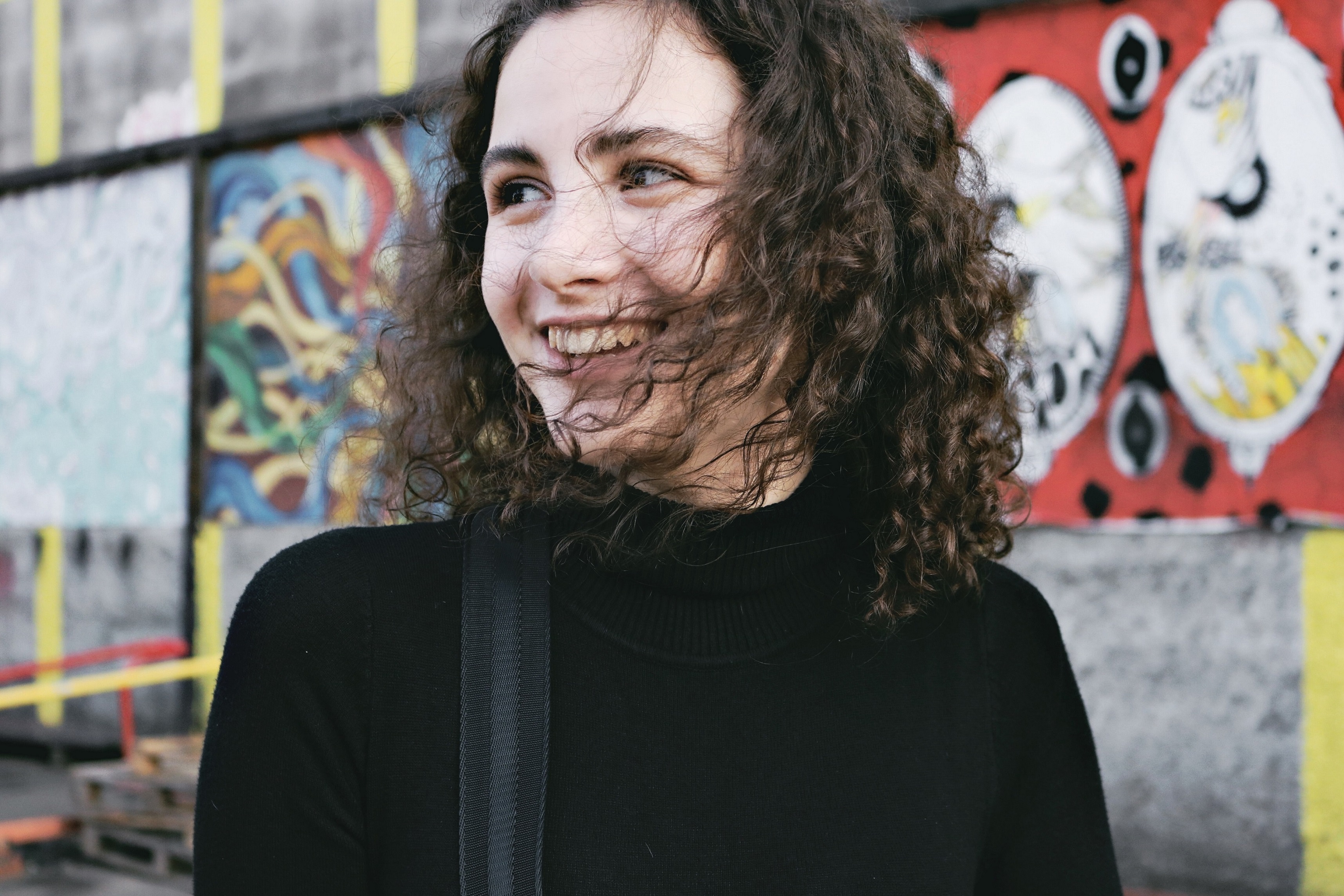 young woman smiles with her hair blowing in the wind