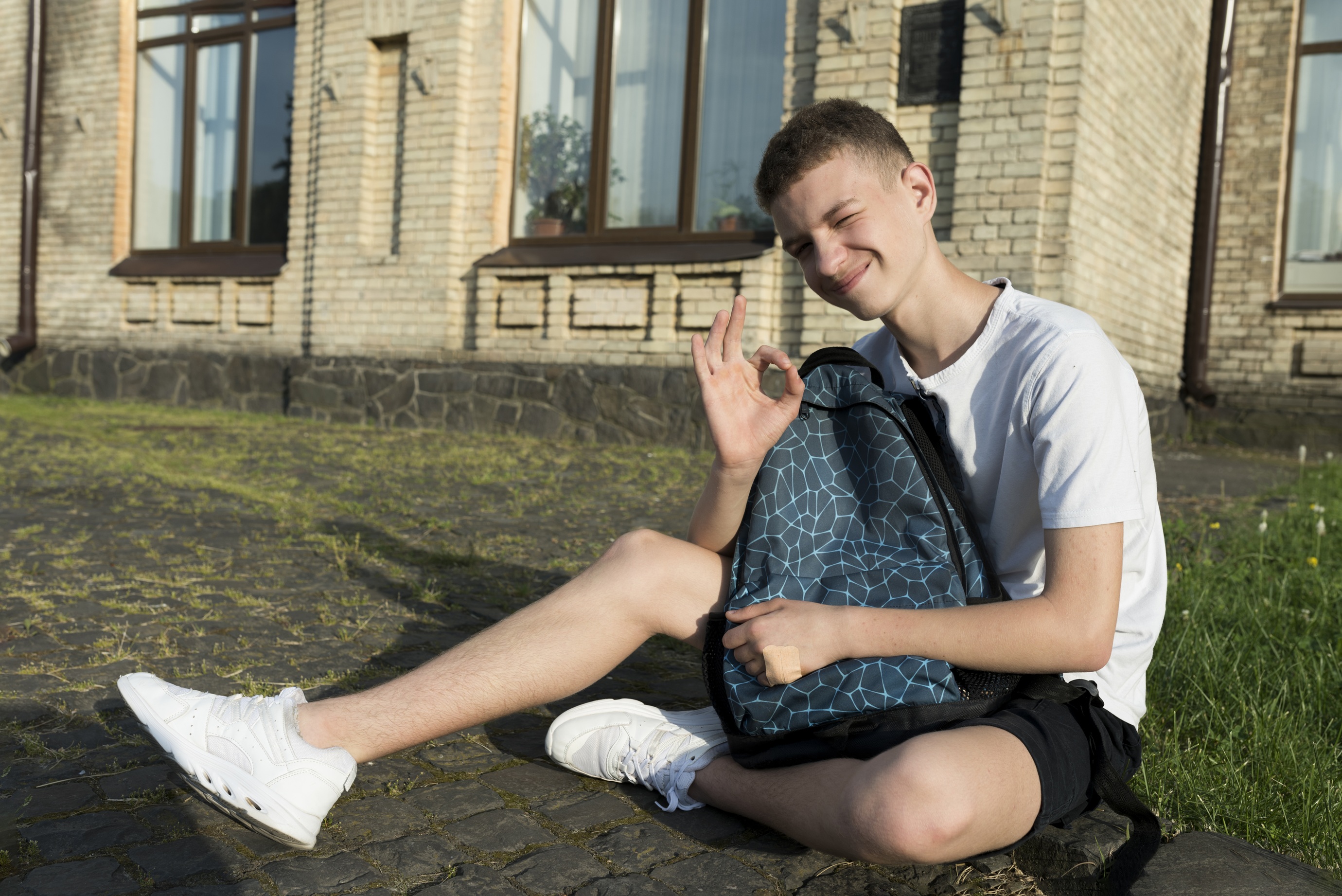 young man sitting outside give the okay gesture