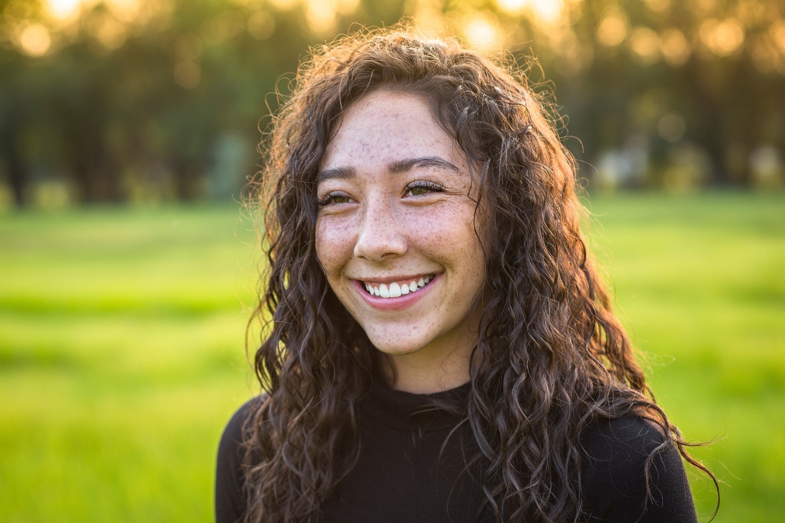 close up of smiling young woman outside in the sun