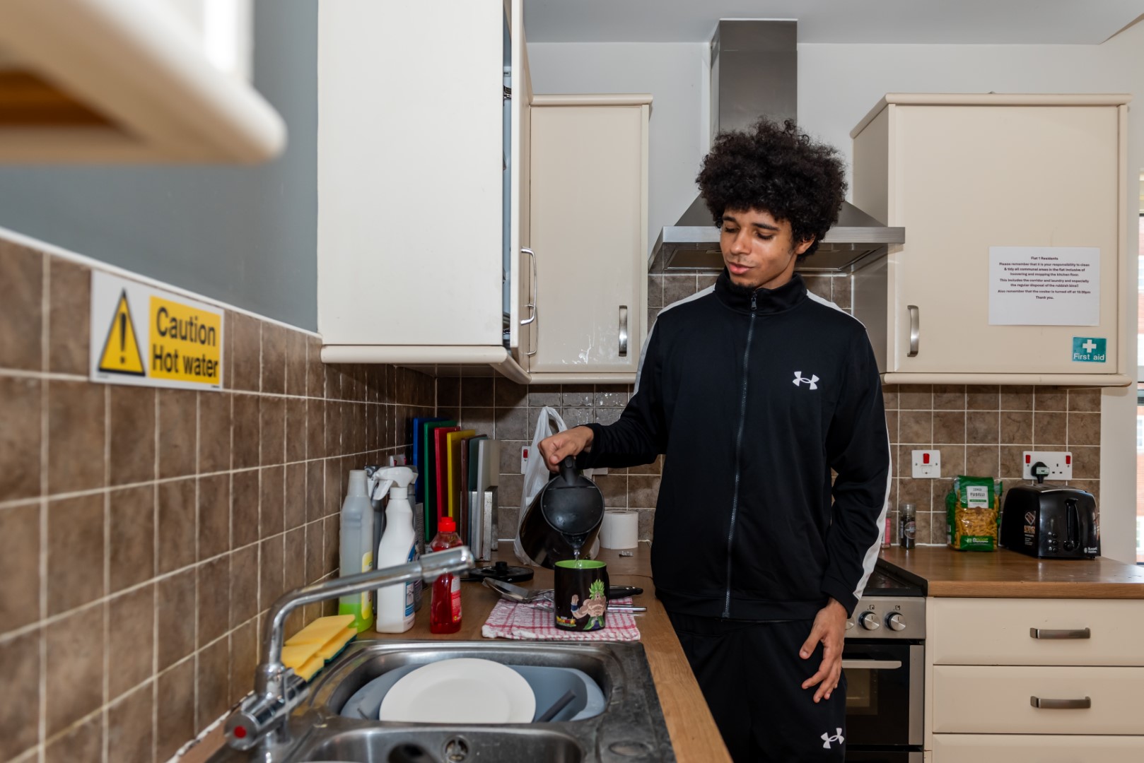 young man makes a cup of team in a Step by Step kitchen